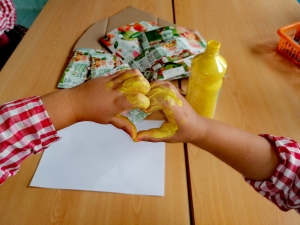 Duas crianças pintaram de amarelo as suas mãos e "desenharam" um coração, carimbando a sua forma em papel, para colocar posteriormente no trabalho.